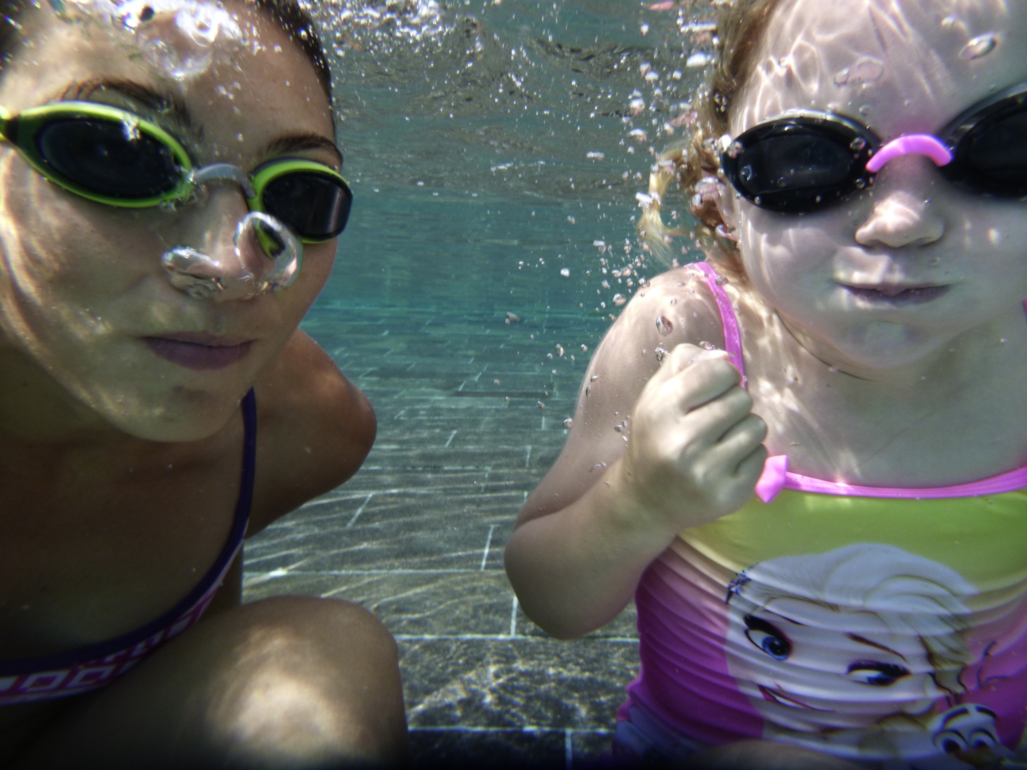 Zwei Kinder mit Schwimmbrillen unter Wasser